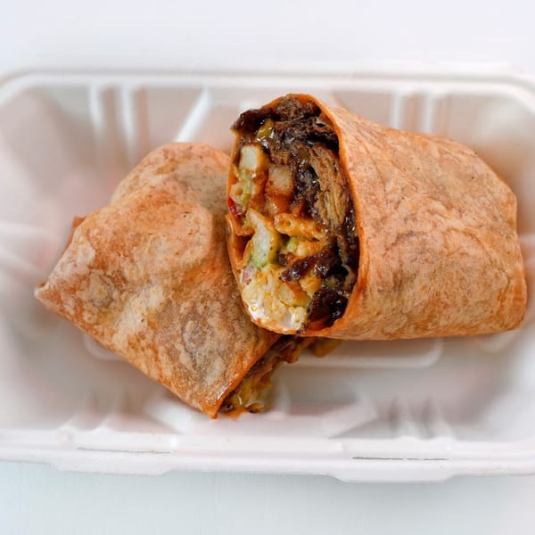 Two Vegan Mob burritos, one cut open to show vegan BBQ, mac and cheese, and other fillings.