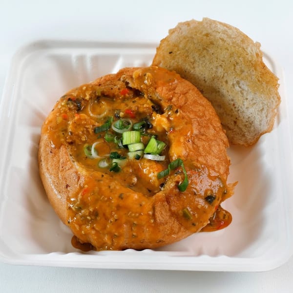 Vegan Mob's vegan gumbo in a bread bowl, garnished with green onions, served on a white tray.
